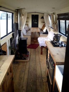 the inside of a camper with wood flooring and white drapes on the windows