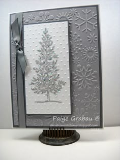 a christmas card with a silver tree on the front and white background, which has snowflakes all over it