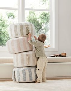 a little boy playing with some pillows in front of a window