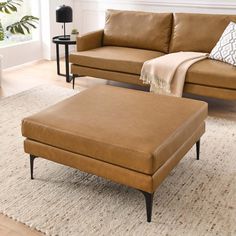 a tan leather couch and ottoman in a living room