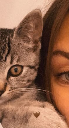 a woman is holding a cat with a heart on it's chest and looking at the camera