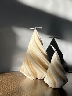 two white vases sitting on top of a wooden table