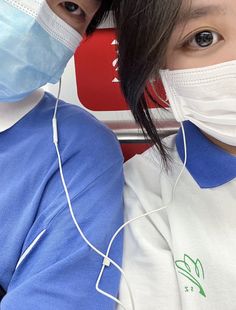 two people wearing face masks and listening to music