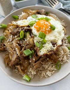 a white plate topped with rice, meat and an egg