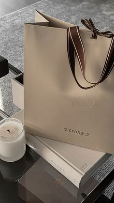 a white bag sitting on top of a table next to a candle and some books