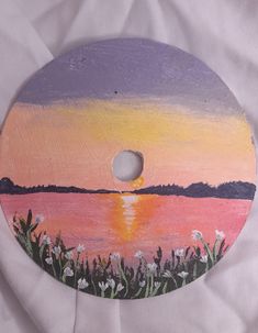 a painted wooden disk with flowers and water in the background