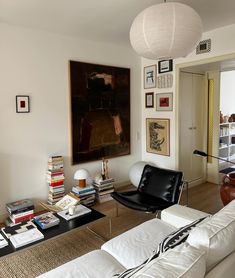 a living room filled with white furniture and lots of books on top of a table