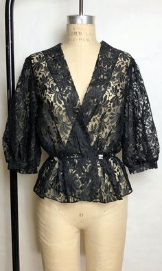 "DETAILS * romantic black lace blouse * puffed half sleeves * rhinestone buttons * elastic waist * completely sheer * perfect for a boudoir photoshoot ERA: 1980s LABEL: n/a SIZE: Medium shoulders: 15\" bust: 36\" (doubled) waist: 26\" sleeve length: 16\" length: 24\" FABRIC: feels like nylon COLOR: black CONDITION: excellent, has been dry cleaned! Please contact us about any questions you may have regarding condition before purchasing. We strive to mention and photograph as many flaws to note ho Black Lace Tops For Party, Black Lace Party Tops, Black Lace V-neck Top, Fitted Black Blouse With Lace Work, Black Feminine Lace Top With Lace Trim, Feminine Black Lace Top With Lace Trim, Black Scalloped Lace Top For Evening, Delicate Lace Blouse For Party, Party Blouse With Delicate Lace