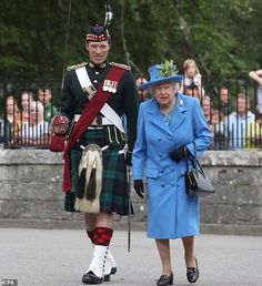 an older man and woman in kilts walking down the street