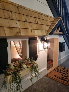 a doll house with flowers and plants in the window sill next to a stair case