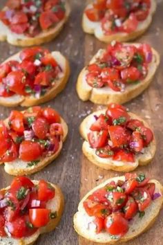 several pieces of bread topped with tomatoes and chopped green onions on top of a wooden table