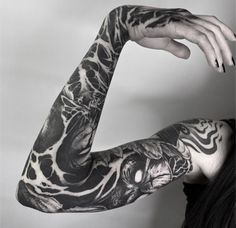 a woman with black and white tattoos on her arm is holding up her hand to the camera