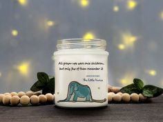 a candle with an elephant on it sitting next to some wood beads and green leaves