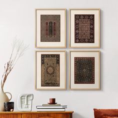 four framed art pieces hang on the wall above a dresser in a room with white walls