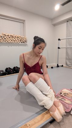 a woman sitting on top of a mat with her leg in bandages and shoes next to her