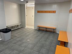 an empty room with benches and trash cans