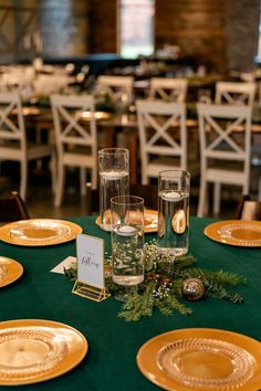 the table is set with gold plates and place settings