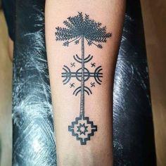 a tattoo on the arm of a person with a cross and tree in the middle