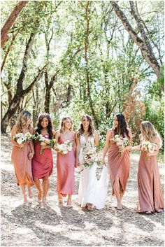 a group of women standing next to each other in front of trees and flowers on the ground