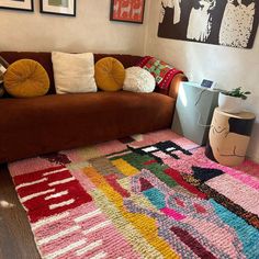 a living room with a brown couch and colorful rugs on the floor in front of it