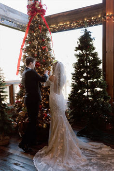 bride in white wedding dress and groom in black suit hanging an ornament on a christmas tree Christmas Chapel Wedding, Christmas Eve Wedding Ideas, Intimate Christmas Wedding, Southern Christmas Wedding, Small Christmas Wedding Ideas, Christmas Wedding Ceremony Backdrop, Christmas Wedding Ideas Decorations, Christmas Trees At Wedding, Christmas Wedding Church Decor