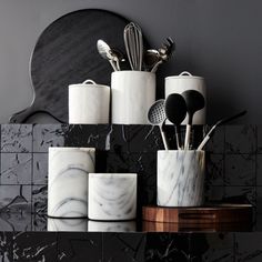 marble kitchen utensils and spoons are arranged on a black countertop in front of a mirror