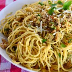 a white bowl filled with pasta and meat on top of a checkered table cloth