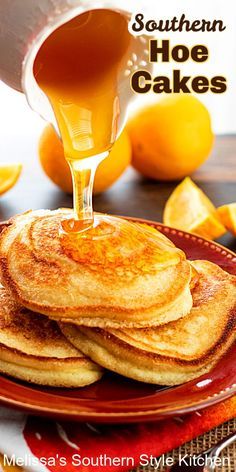 pancakes on a plate with syrup being poured over them and oranges in the background