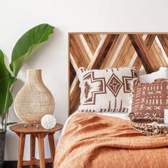 a bed with pillows and blankets on top of it next to two side tables in front of a white wall