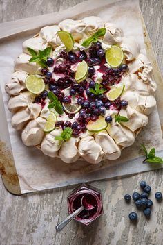 an uncooked pie with blueberries and limes on it next to some berries