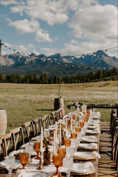 a long table is set up with wine glasses and plates for an outdoor dinner party