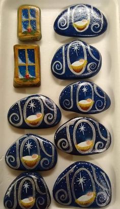 some blue and white painted rocks with pictures on them in front of a small window