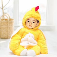 a baby in a yellow chicken costume sitting on the floor