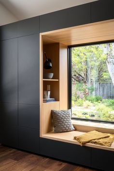 a window seat in front of a large window next to a wooden floor and wall