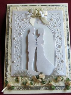 a wedding card with a bride and groom silhouettes on the front, surrounded by flowers