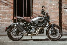 a motorcycle parked in front of a brick building with bars on the windowsills