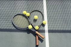 two tennis rackets and three balls on a court