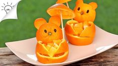 some oranges are carved to look like bears with umbrellas in their mouths on a plate