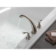 a white bath tub with two faucets and soap dispenser next to it