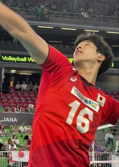 a young man is playing volleyball in front of an arena full of people and fans