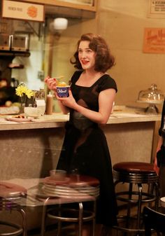 a woman standing in front of a counter holding a bowl