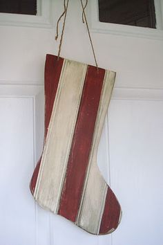 a striped christmas stocking hanging from a door with two windows in the back ground