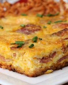 a close up of a piece of food on a plate with green onions and cheese