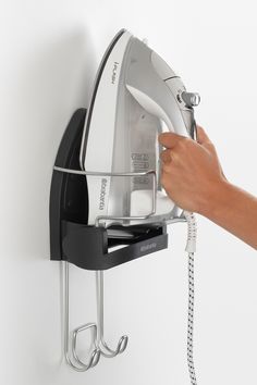 a person is using an iron to dry clothes on a wall mounted ironing board