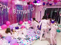 two girls in pink pajamas are on a bed with balloons and streamers