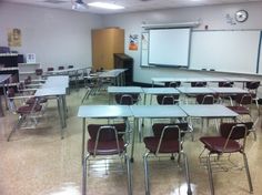 an empty classroom with desks and chairs in front of a whiteboard on the wall