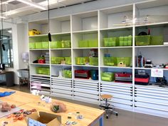 a room filled with lots of white shelves and green bins