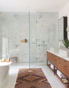 a bathroom with a large rug on the floor and a glass shower door that is open