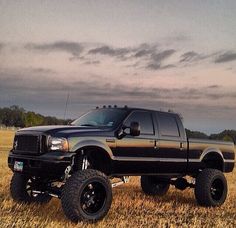 a large black truck parked on top of a dry grass field