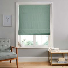 a living room with a chair, window and green roller shades on the windowsill